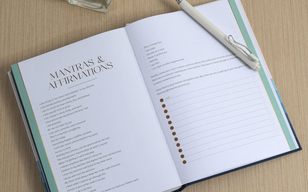 A person writing in a journal with a pen, the journal open on a table.